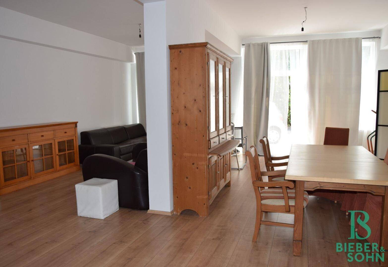 Geräumiger offener Wohn- und Essbereich mit Holzboden und großen Fenstern, hell und einladend.