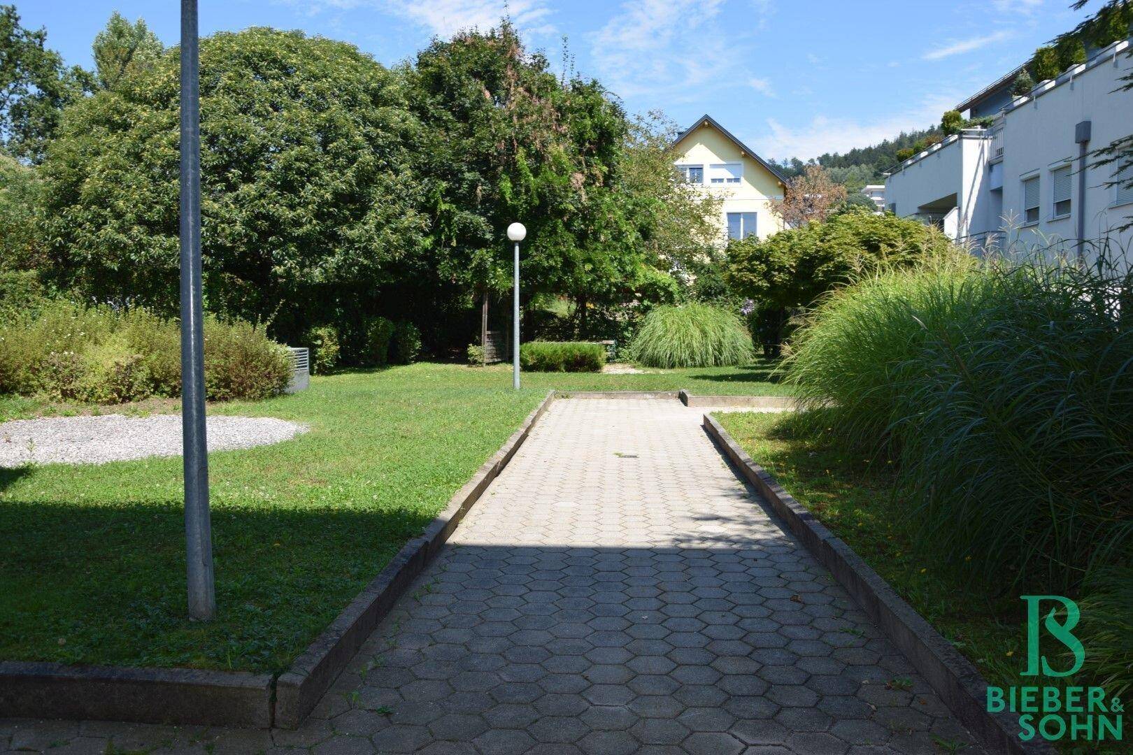 Gepflegte Grünfläche mit einem gepflasterten Weg und Bäumen, ideal für Erholung im Freien.