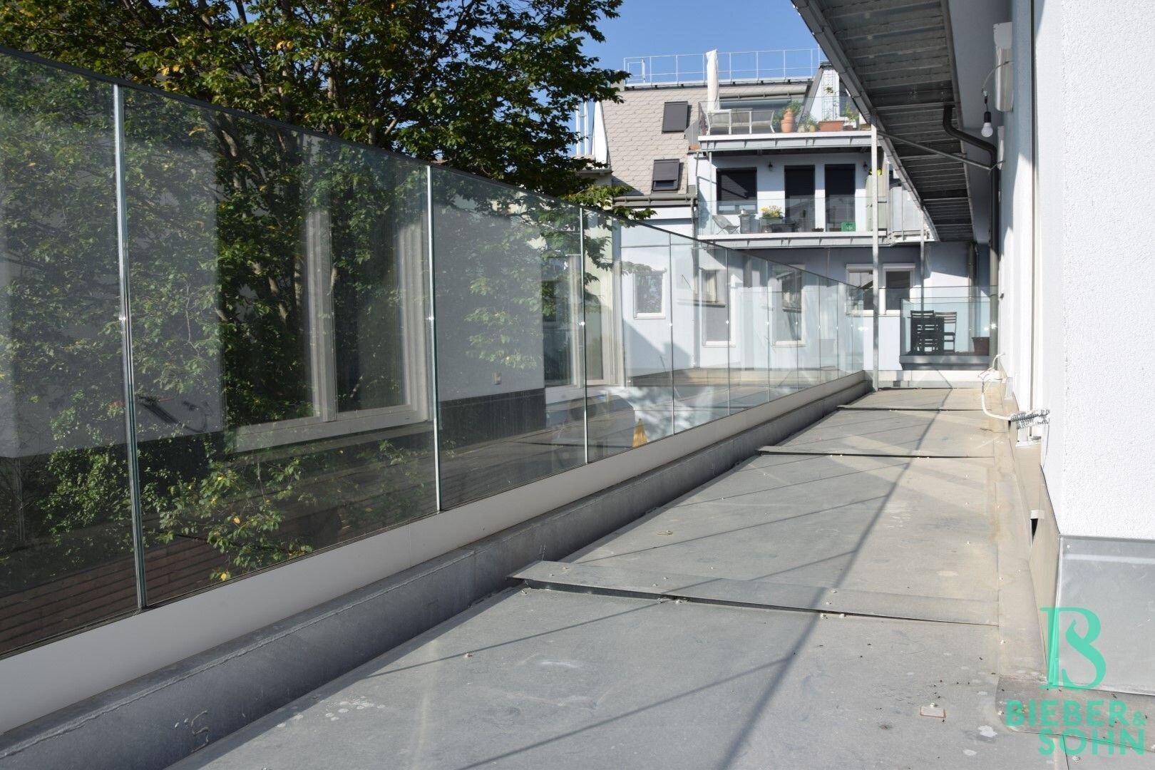 Große, begehbare Fläche mit Glasgeländer und Blick auf umliegende Gebäude.