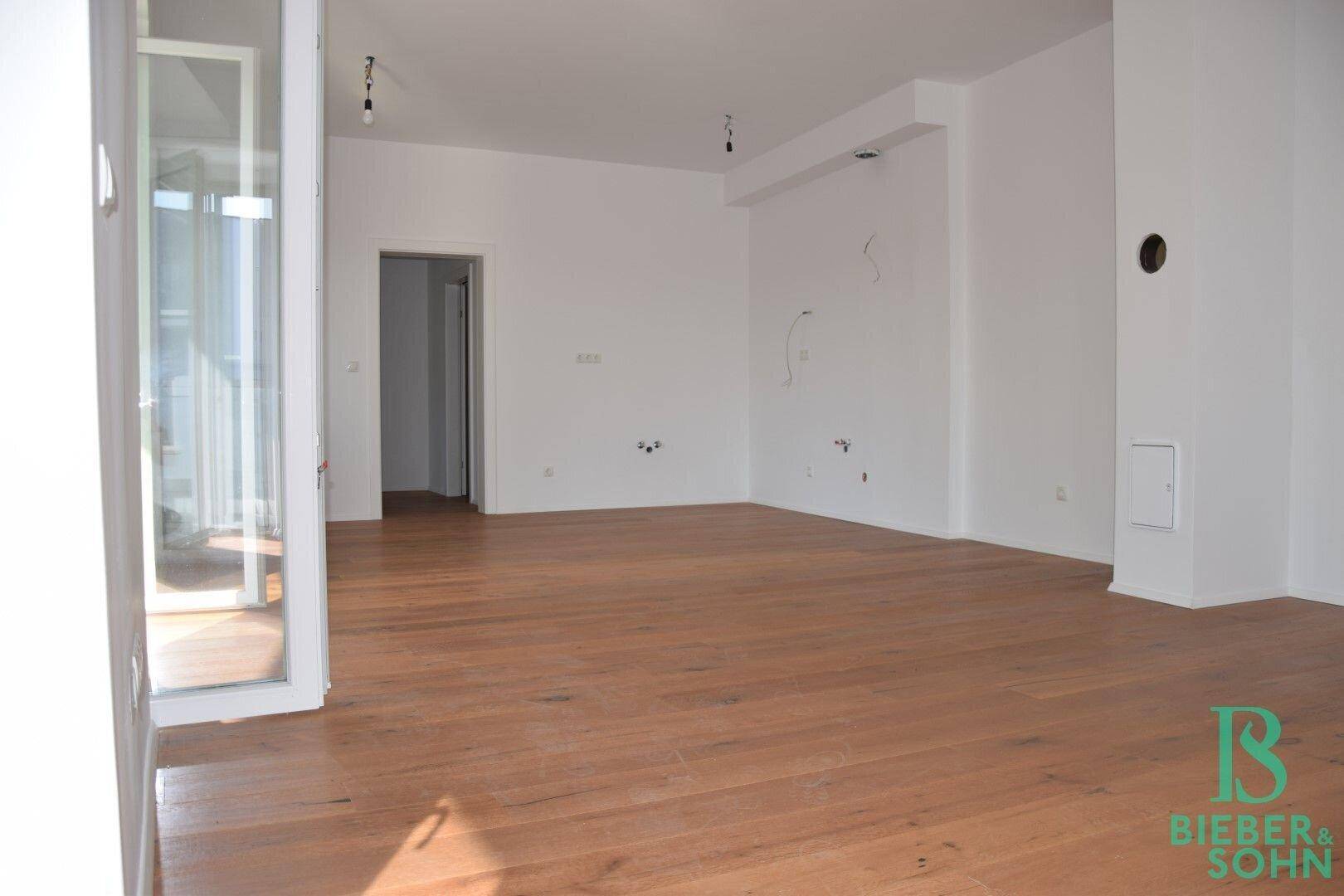 Geräumiger, heller Raum mit Holzboden, ideal für einen offenen Wohnbereich.