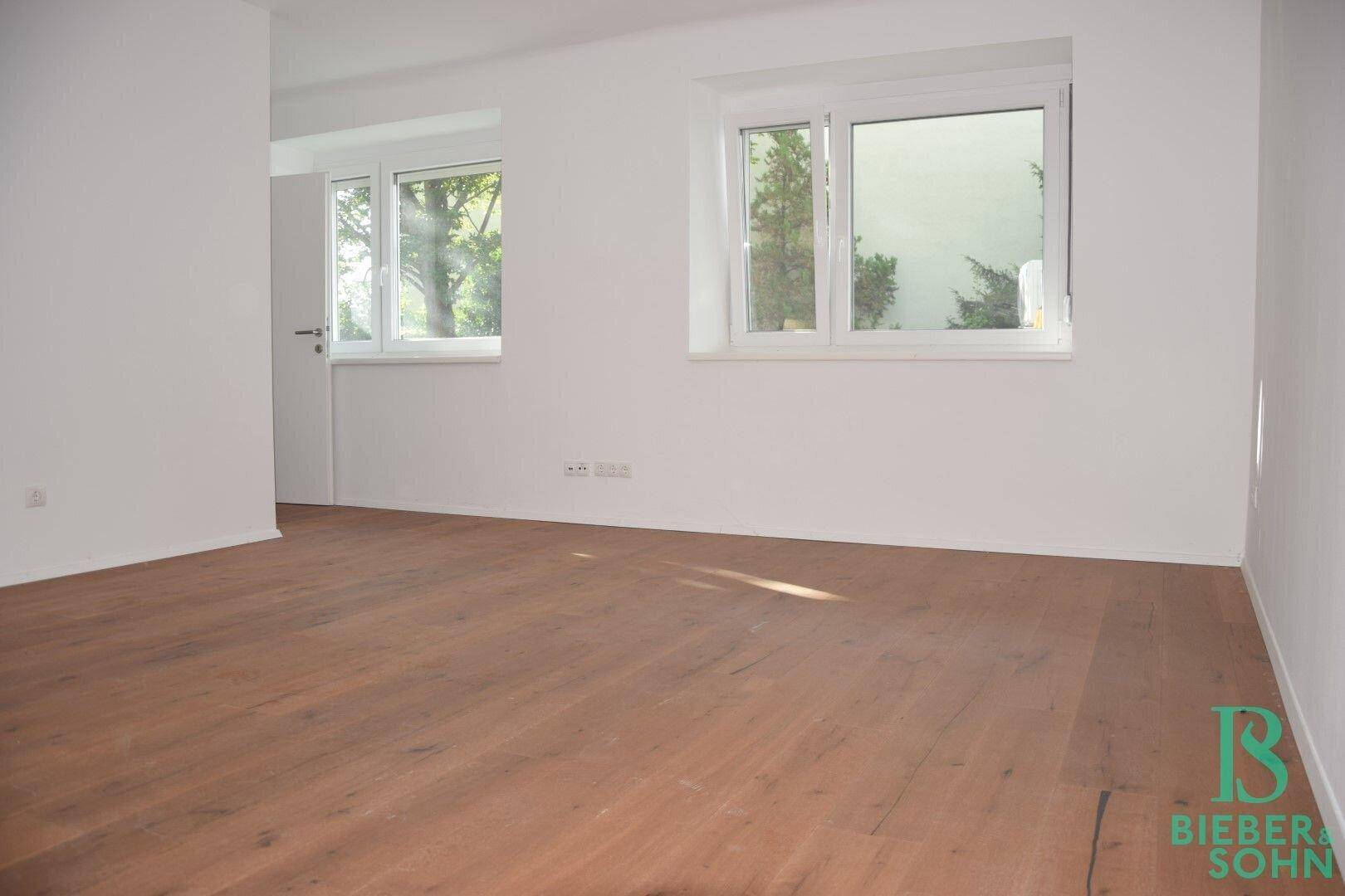 Geräumiges Schlafzimmer mit Holzboden und zwei Fenstern, die für gute Belichtung sorgen.