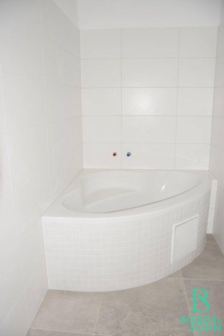 Modernes Badezimmer mit Eckbadewanne und weißen Fliesen, bereit für die Endmontage.