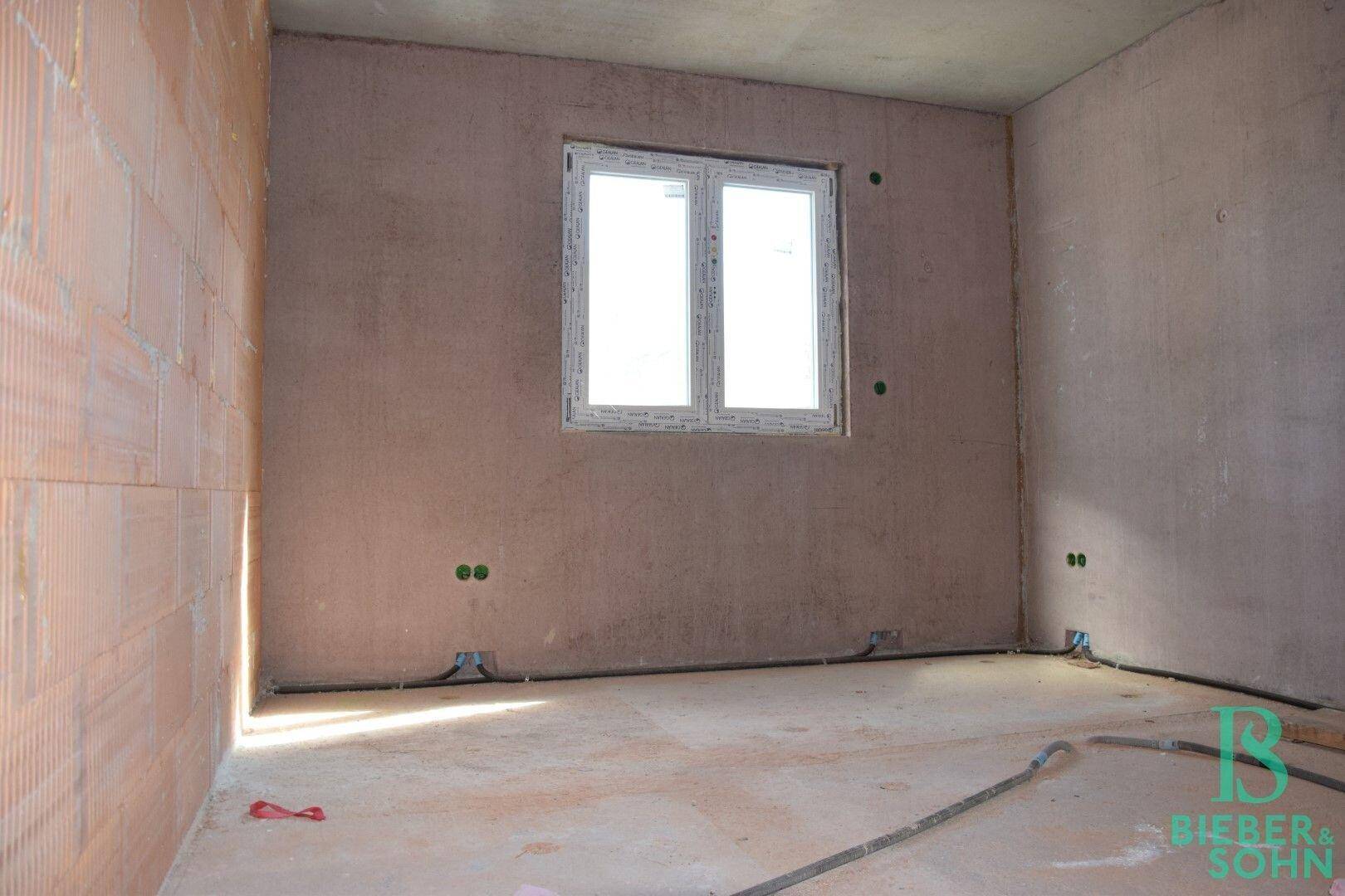 Rohbau-Raum mit einem Fenster, das Tageslicht in den unfertigen Bereich bringt.