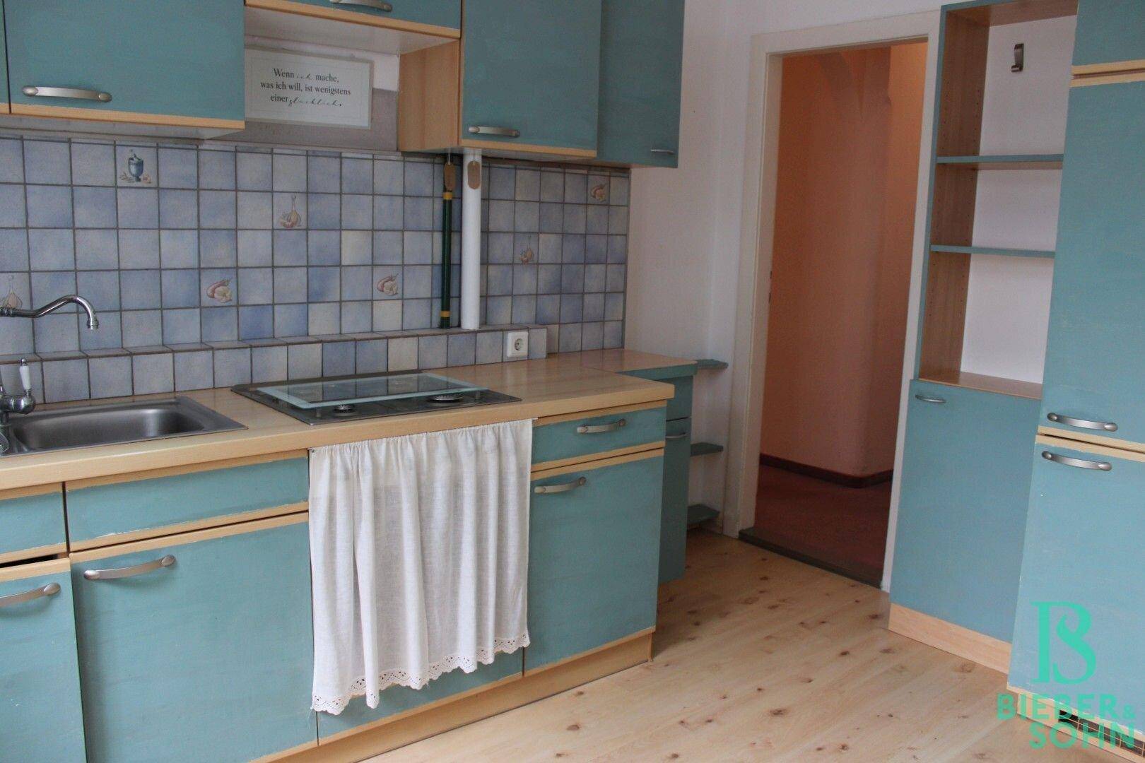 Küche mit hellblauen Schränken, Holzarbeitsplatte und Fliesenrückwand.