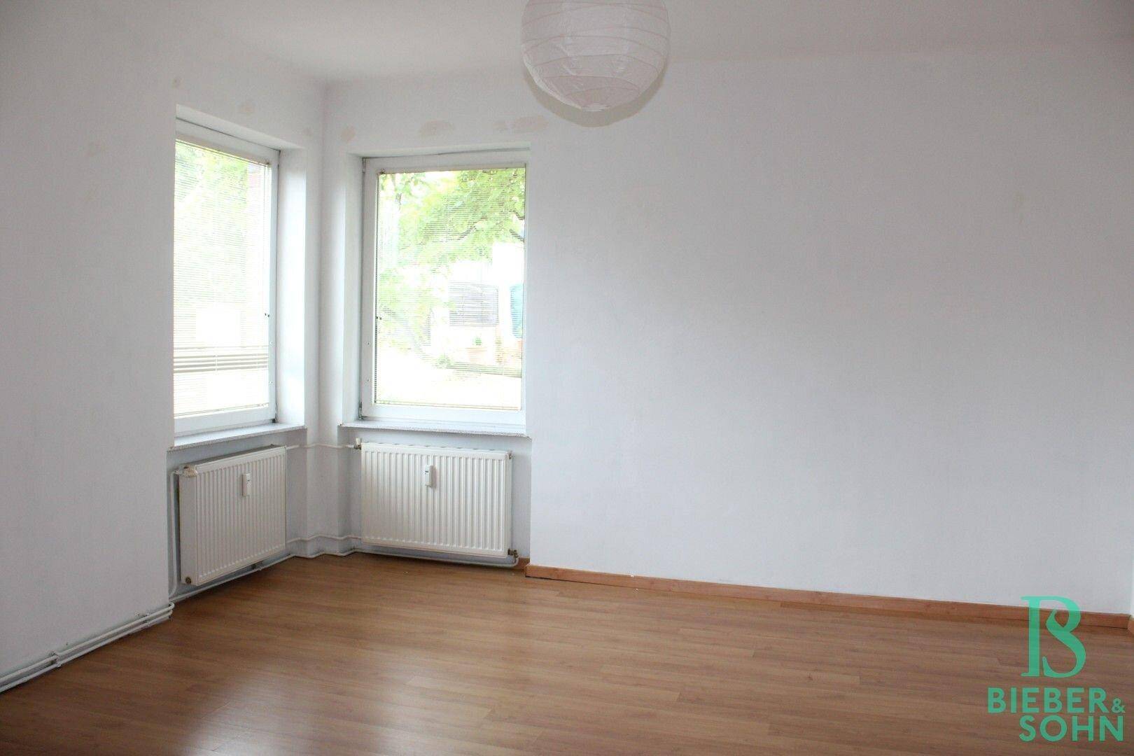 Helles Zimmer mit Holzboden, weißen Wänden und Blick ins Grüne.