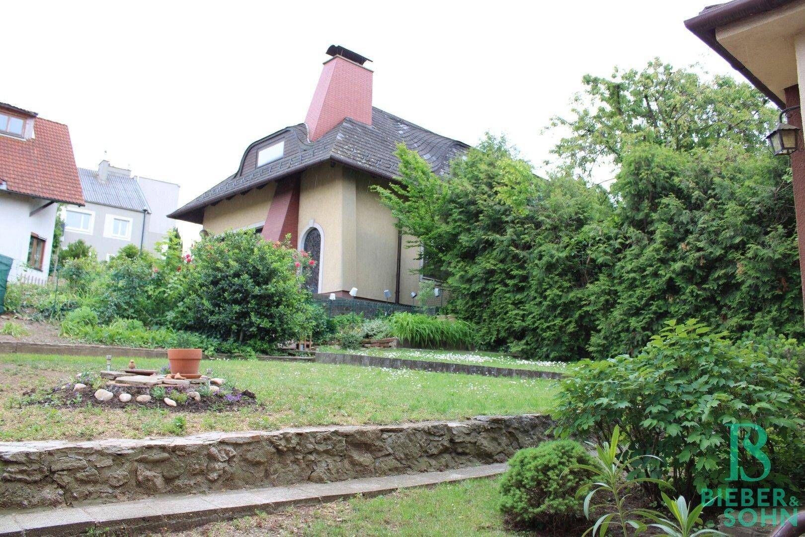 Gartenbereich mit Rasenfläche und einem charmanten Haus im Hintergrund.