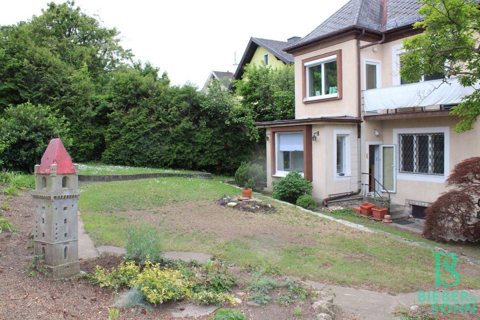 Großer Garten mit Rasenfläche, einem dekorativen Turm und dem Haus im Hintergrund.