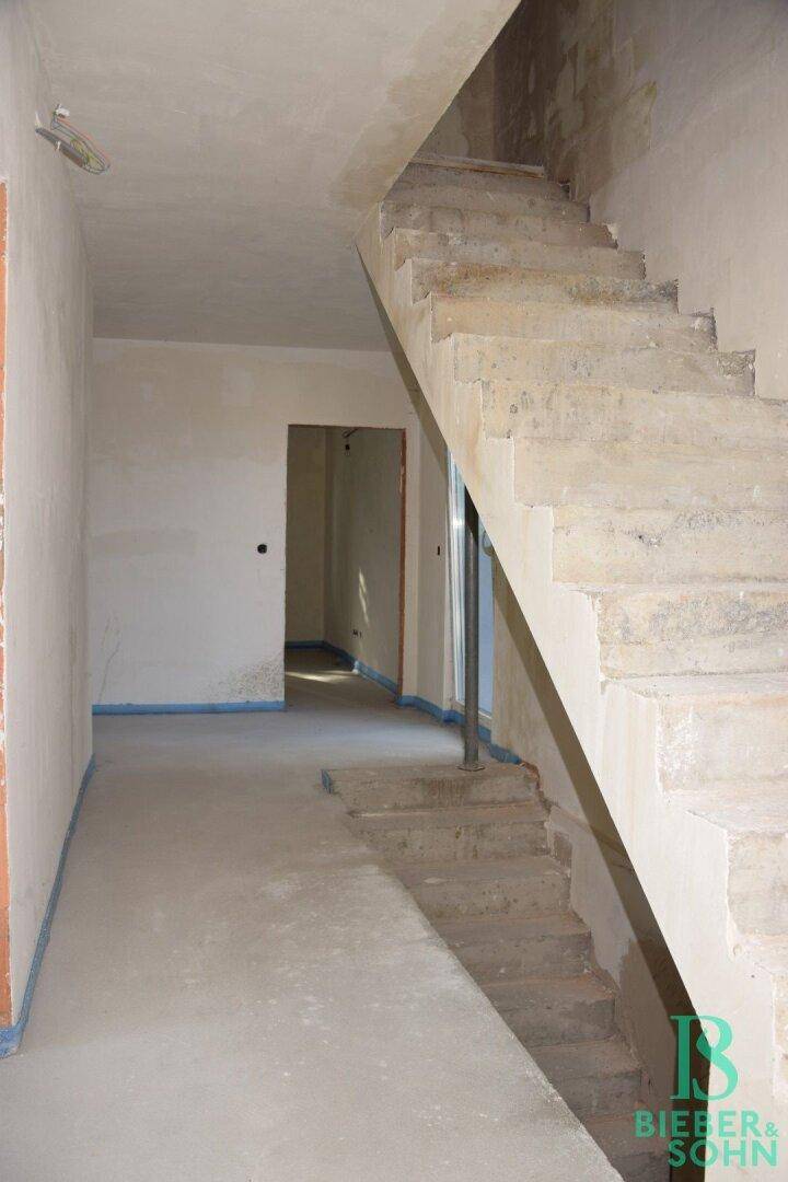 Unfertige Betontreppe in einem Rohbau-Innenraum, die auf den weiteren Ausbau wartet.