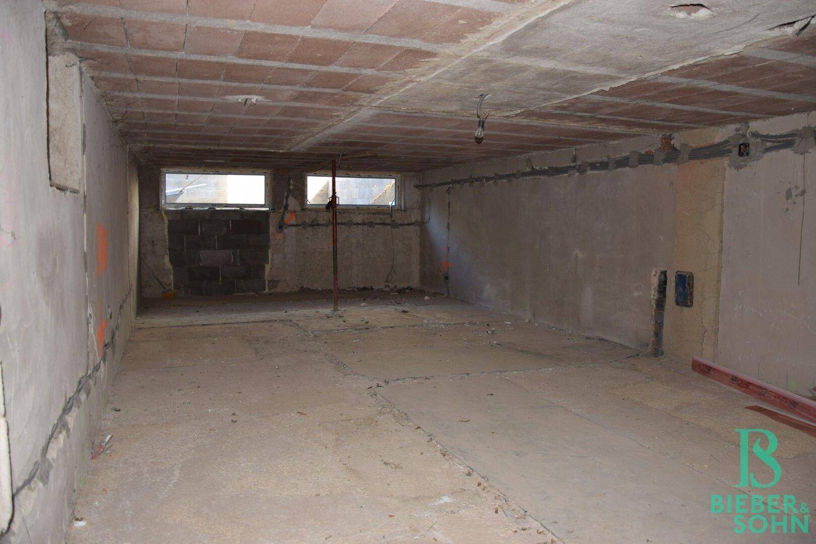 Unfertiger Kellerraum mit kleinen Fenstern und Rohbauwänden, bereit für den Ausbau.
