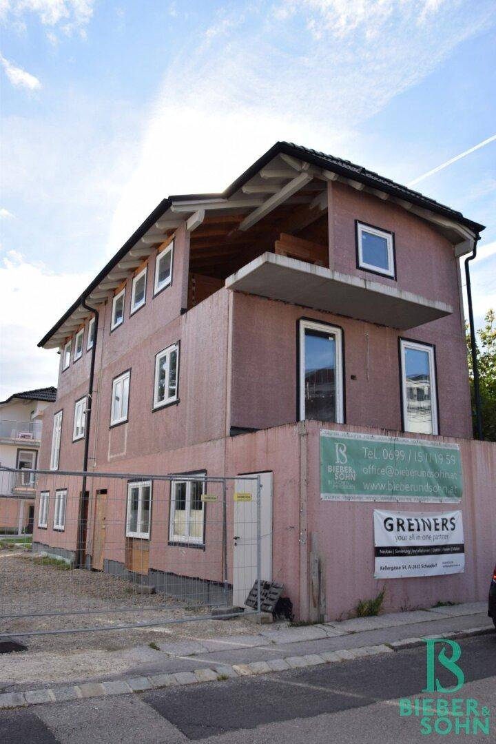 Gebäude im Rohbauzustand mit Werbebannern und sichtbaren Fenstern an der Fassade.