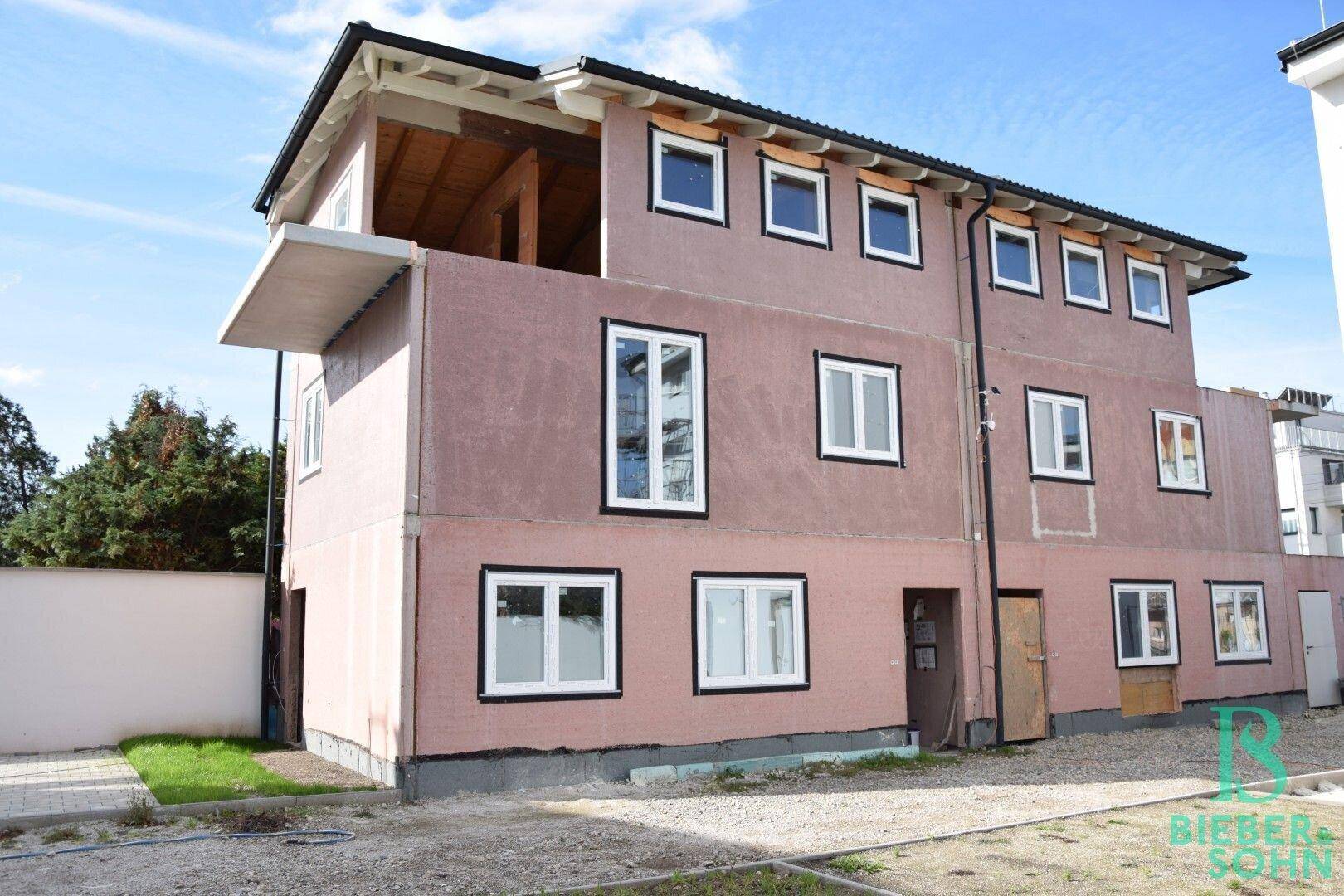 Das Gebäude im Rohbauzustand mit mehreren Fenstern und einem zukünftigen Balkon.