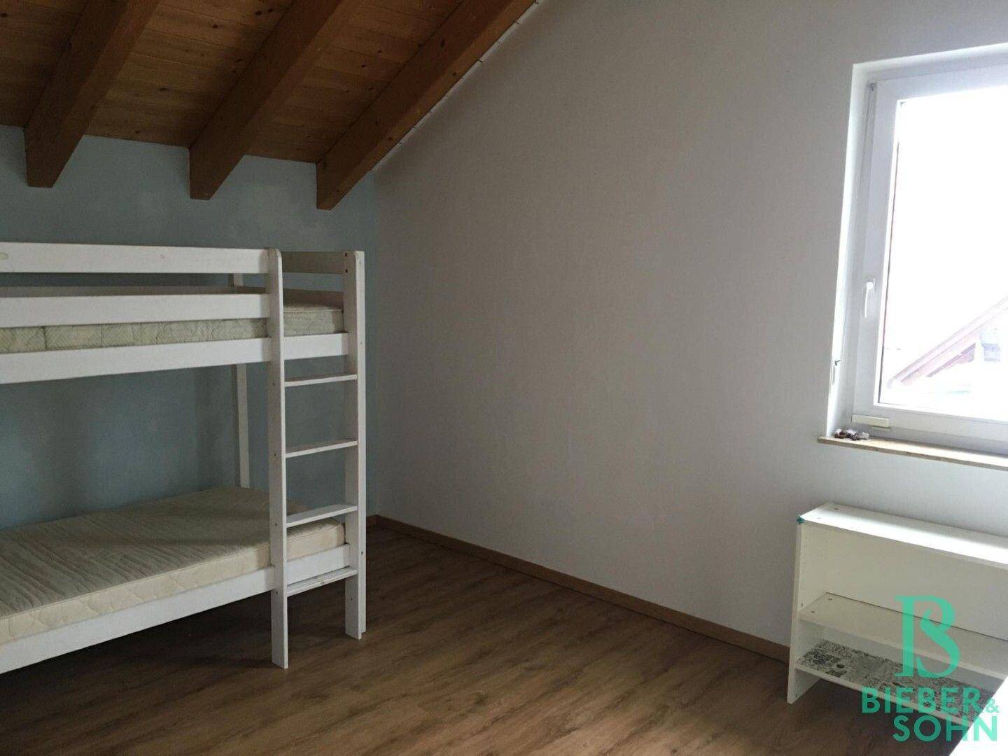 Kinderzimmer im Dachgeschoss mit Etagenbett, Holzboden und einem Fenster.