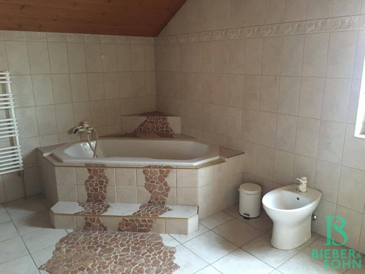 Badezimmer mit Eckbadewanne, Bidet und Fliesen in warmen Farbtönen.
