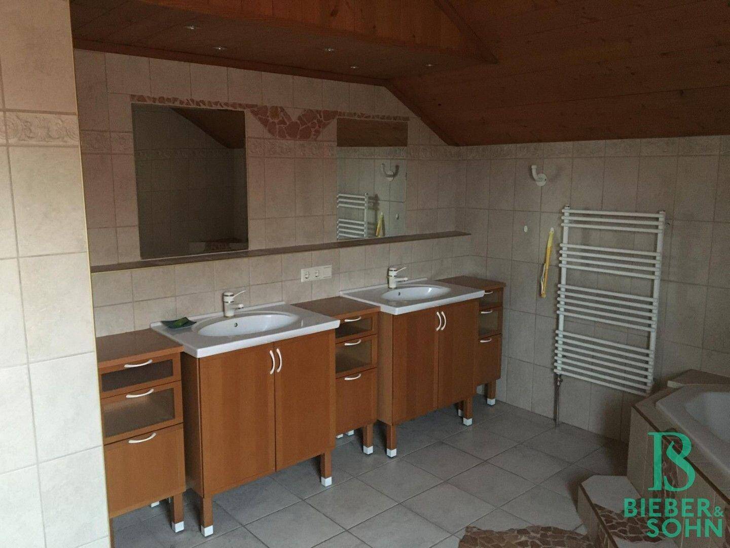 Geräumiges Badezimmer mit Doppelwaschbecken, Fliesenboden und Holzdecke.