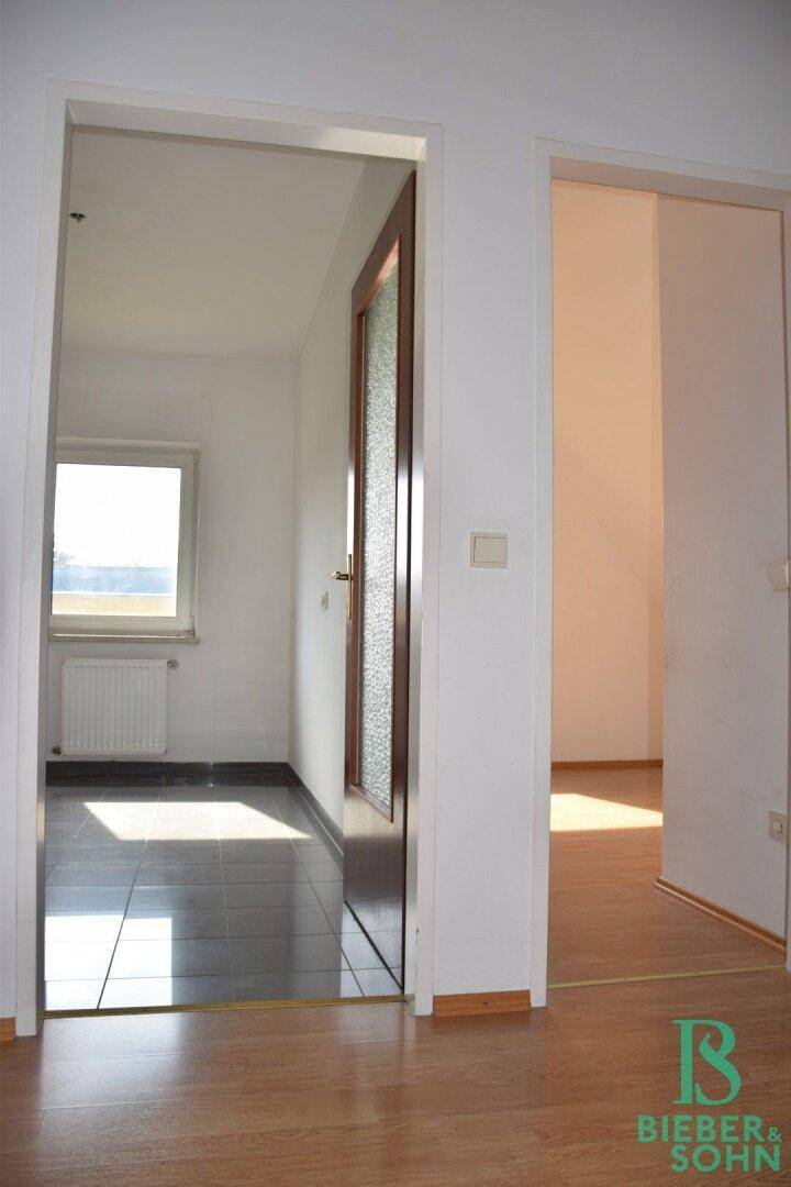 Übergangsbereich mit Laminatboden, der zu einem gefliesten Bereich und einem weiteren Zimmer führt.