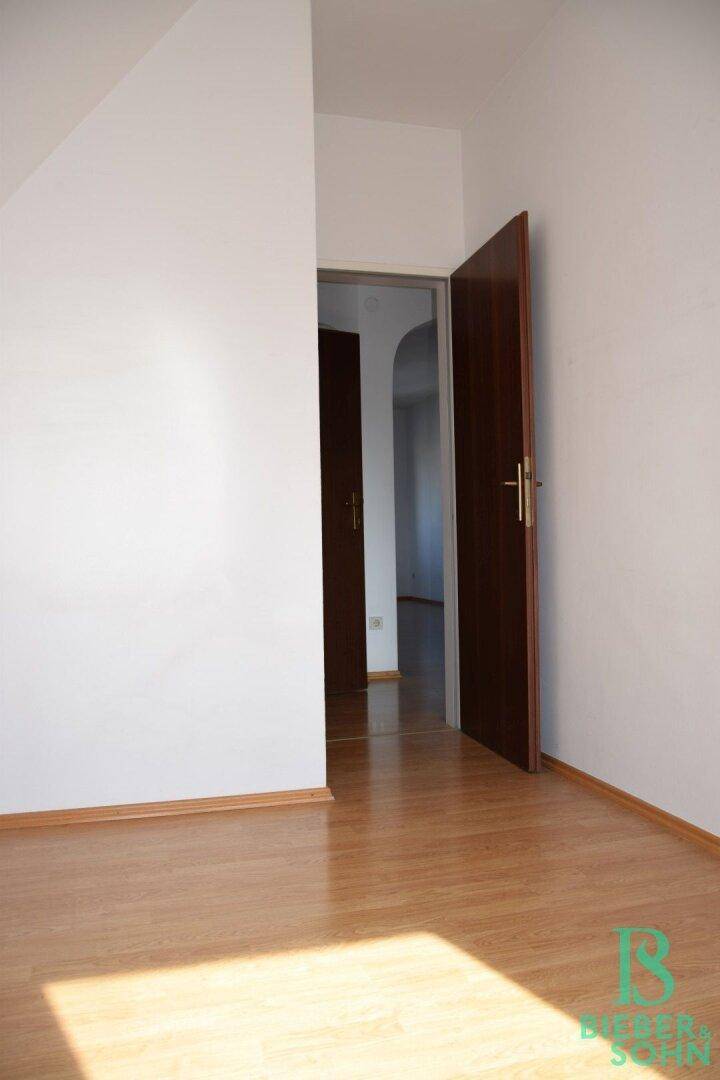 Geräumiger Dachgeschossraum mit Laminatboden und Zugang zu weiteren Zimmern.