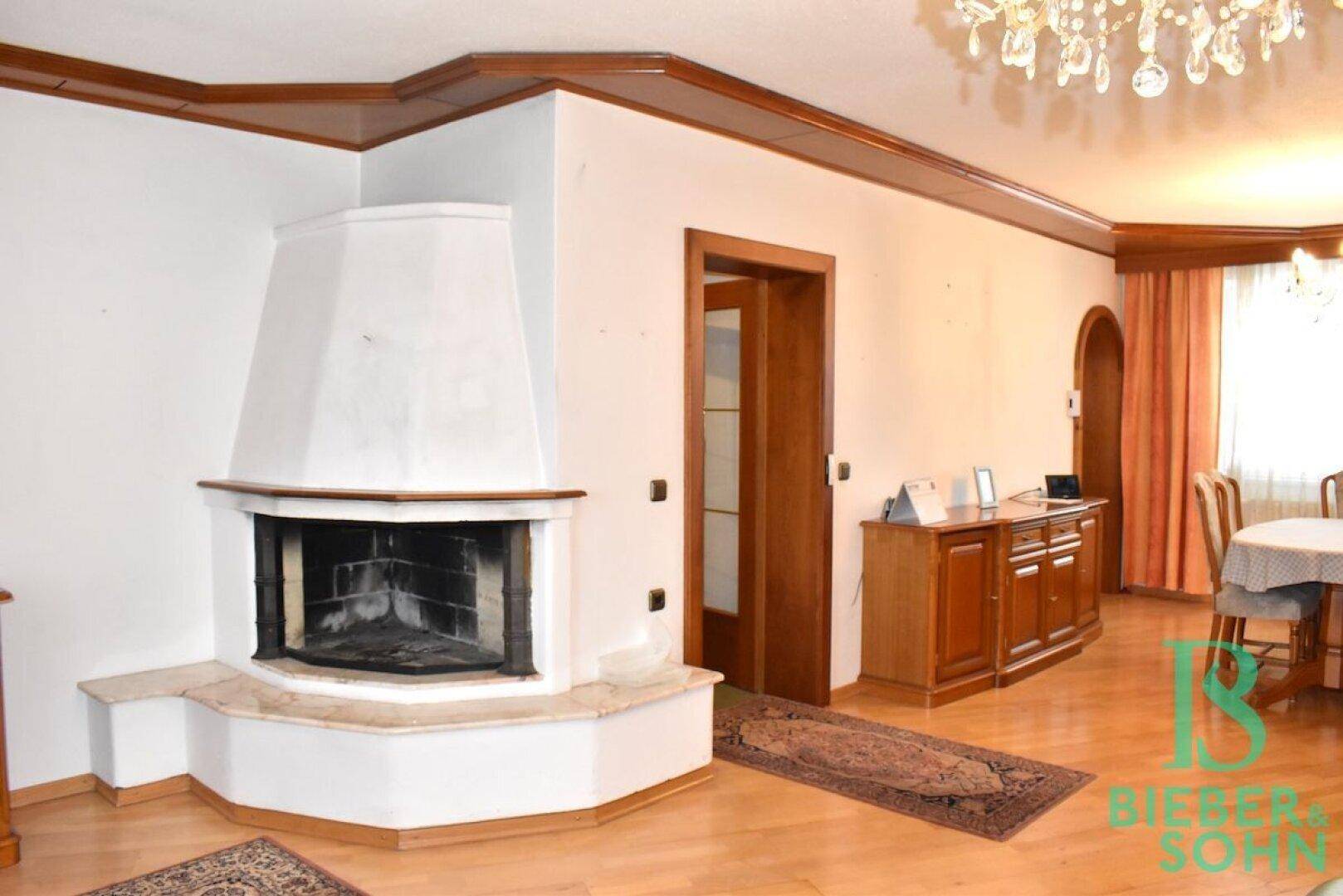 Eckkamin im Wohnbereich mit heller Verkleidung und Holzdetails, umgeben von Parkettboden.