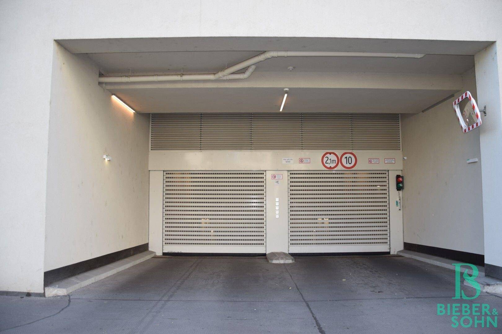 Eingang zu einer Tiefgarage mit zwei Rolltoren und Höhenbegrenzungsschildern.