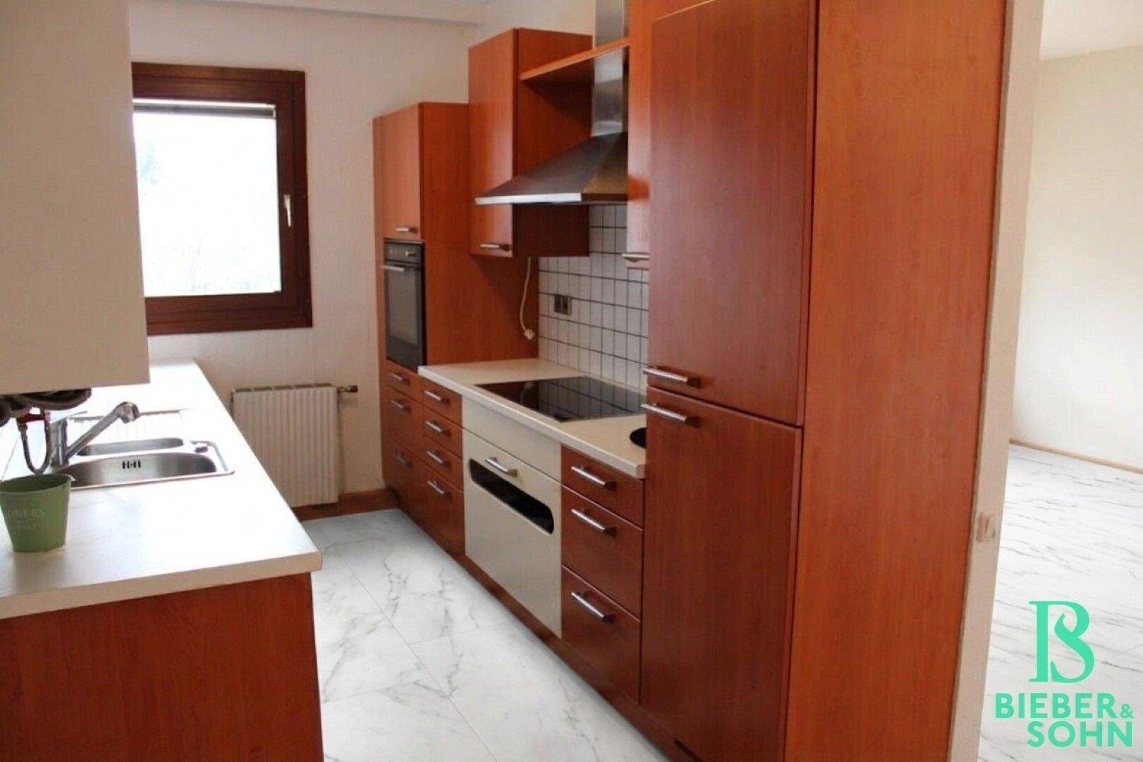 Einbauküche mit Holzfronten, Kochfeld und Dunstabzugshaube.