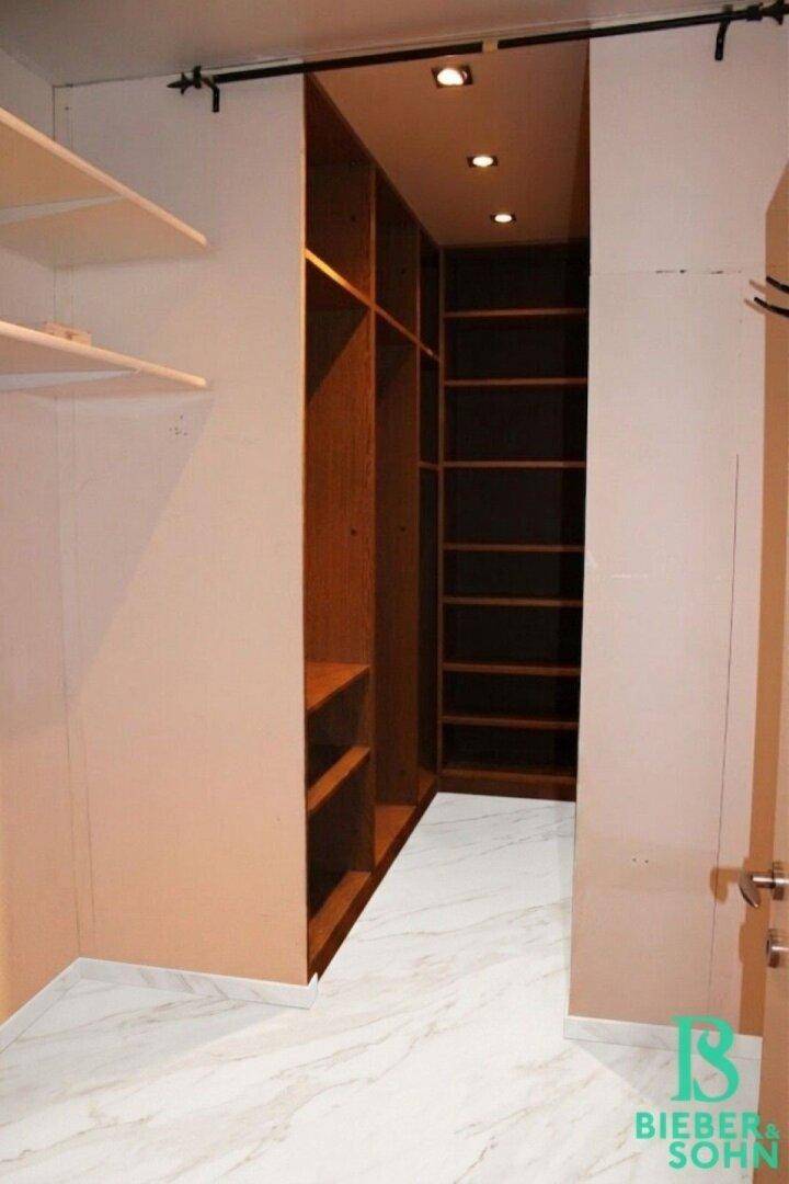 Begehbarer Kleiderschrank mit integrierten Regalen und Beleuchtung.