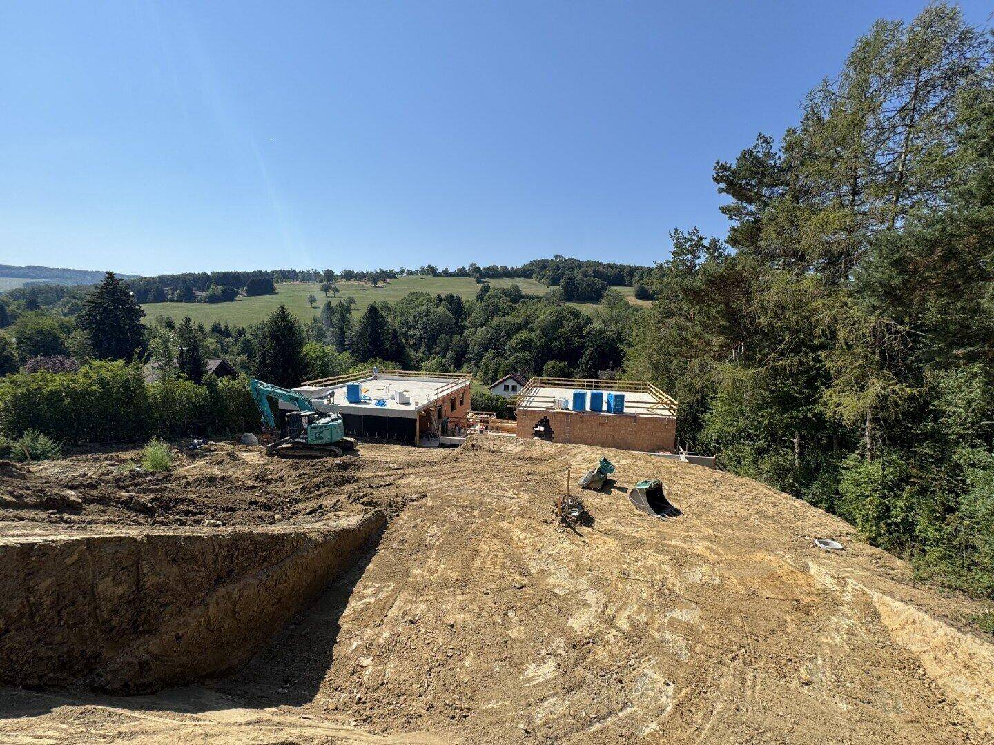 Weitläufige Baustelle mit Erdarbeiten und Blick auf die grüne Hügellandschaft.