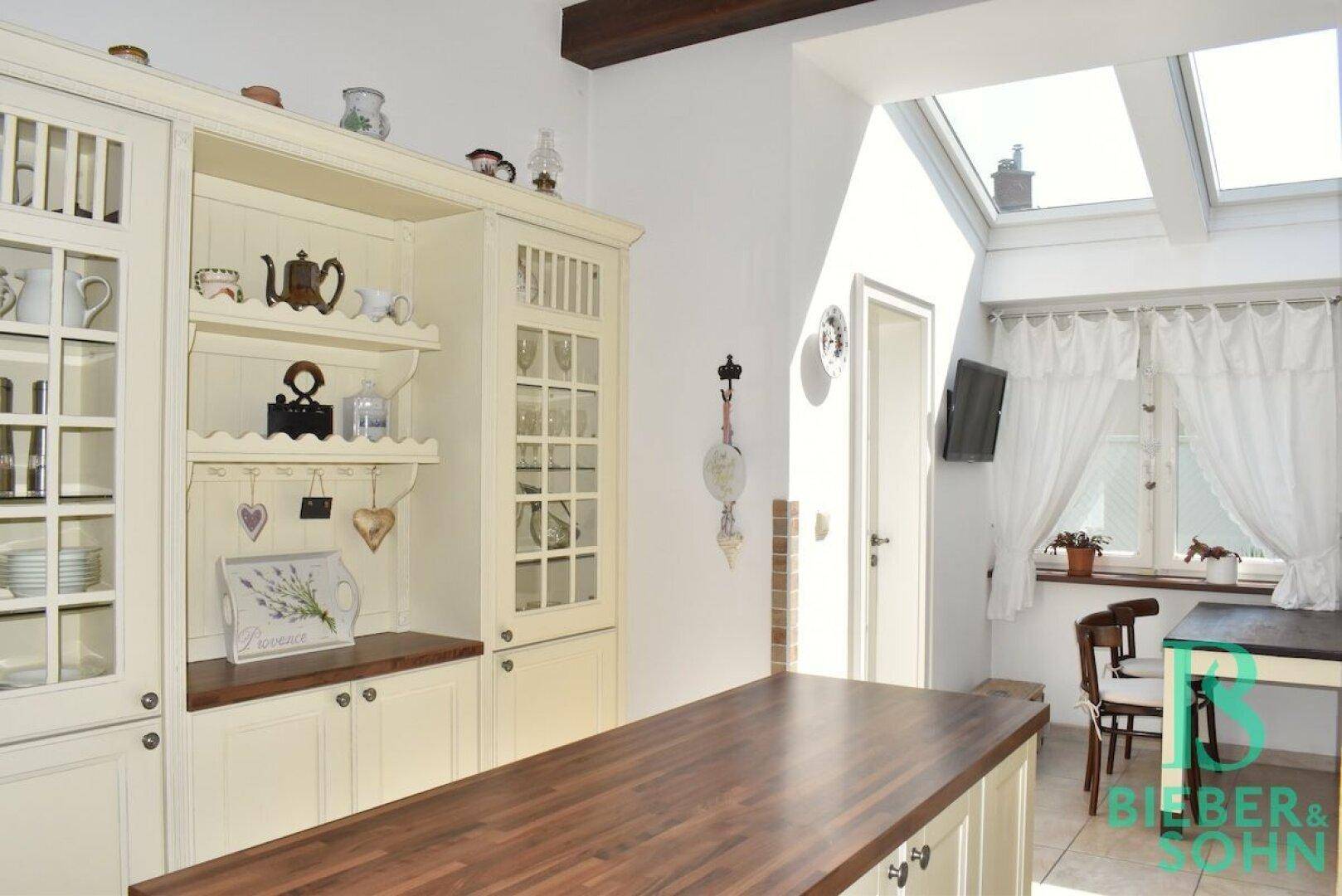Helle Küche mit traditionellen Schränken, viel Stauraum und einem Dachfenster für zusätzliches Tageslicht.