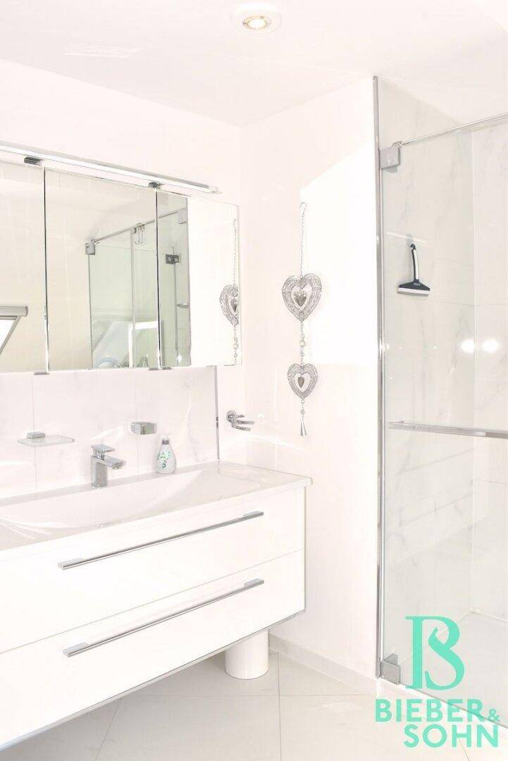 Detailansicht des modernen Badezimmers mit elegantem Waschtisch, Spiegelschrank und geräumiger Glasdusche.