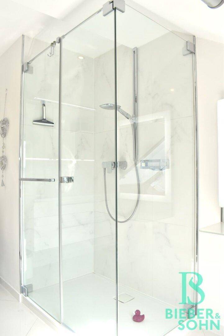 Geräumige, moderne Glasdusche mit Regenduschkopf und klaren Linien im hellen Badezimmer.