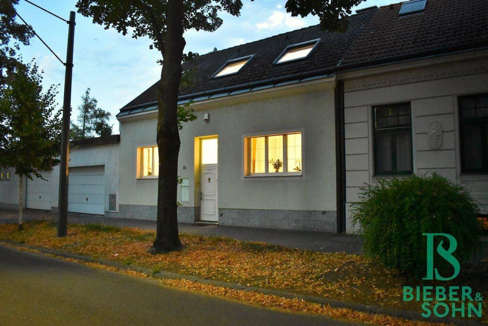 Frontansicht des Hauses in der Dämmerung mit warm beleuchteten Innenräumen.