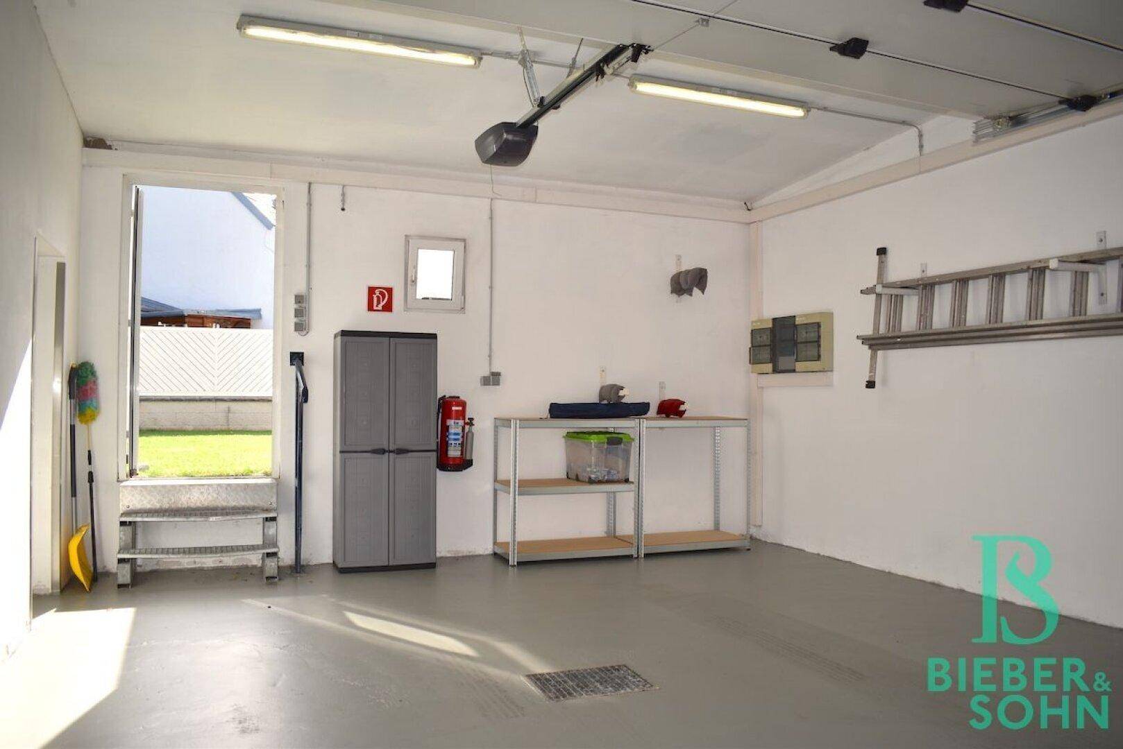 Innenansicht der Garage mit Stauraum, Regalen und Zugang zum Gartenbereich.