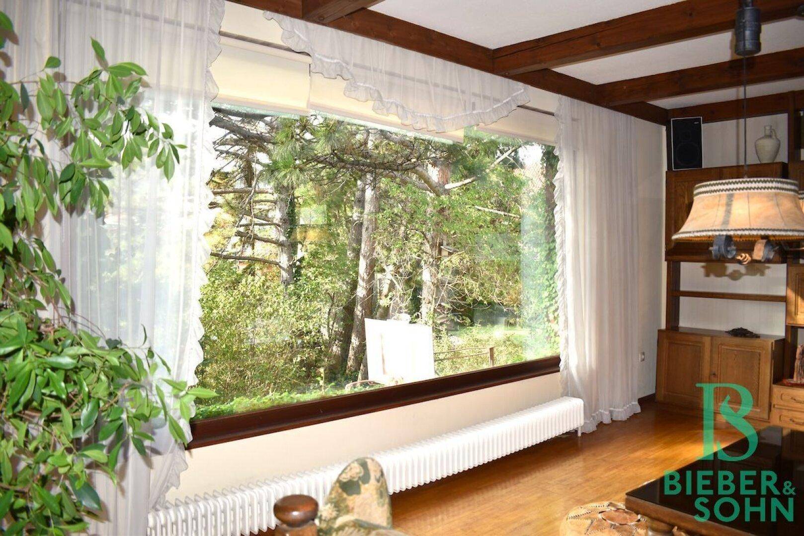 Helles Wohnzimmer mit breiter Fensterfront, die viel Tageslicht und Ausblick bietet.