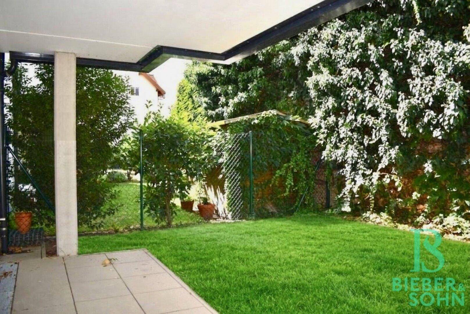 Gepflegter Gartenbereich mit Rasenfläche und üppiger Bepflanzung an der Grundstücksgrenze.