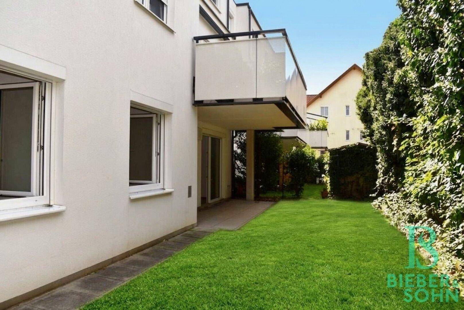 Außenansicht des Gebäudes mit Balkon und gepflegtem Rasenbereich im Vordergrund.