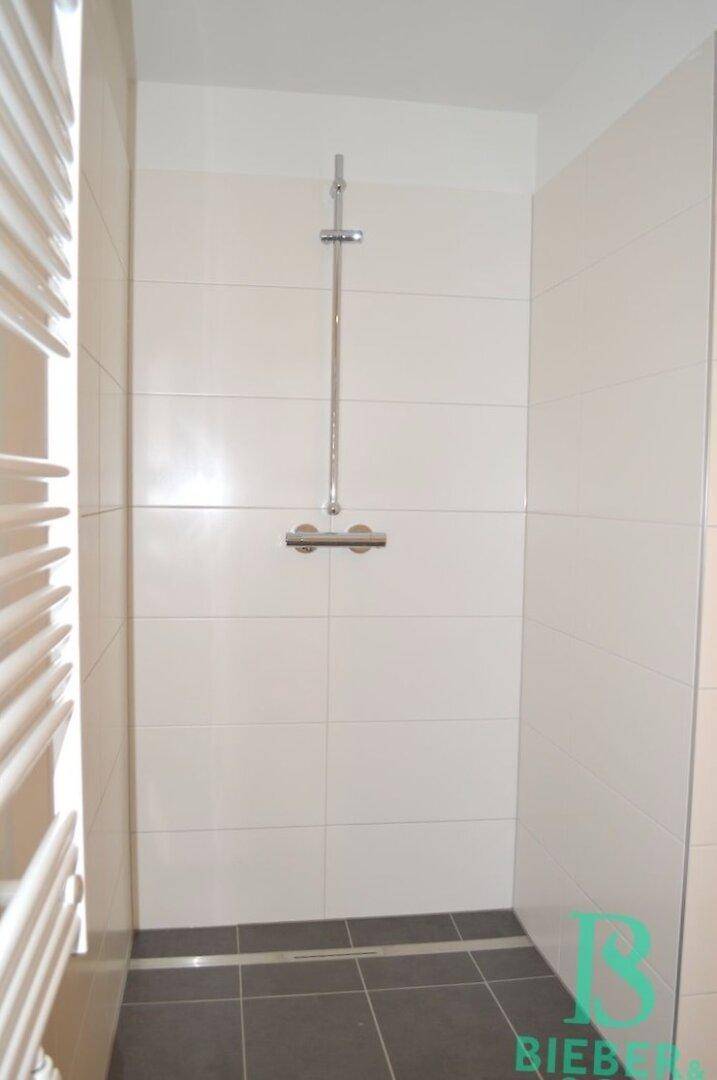 Duschbereich im Badezimmer mit modernen Fliesen und einer praktischen Duschstange.