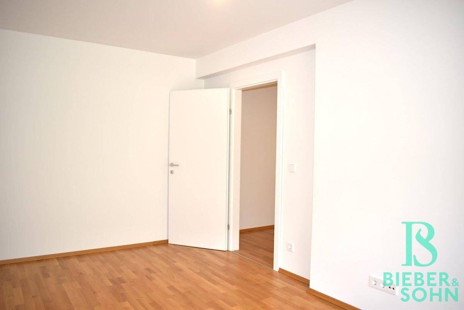 Schlichtes Zimmer mit Parkettboden und weiß gestrichenen Wänden, bereit zur Einrichtung.