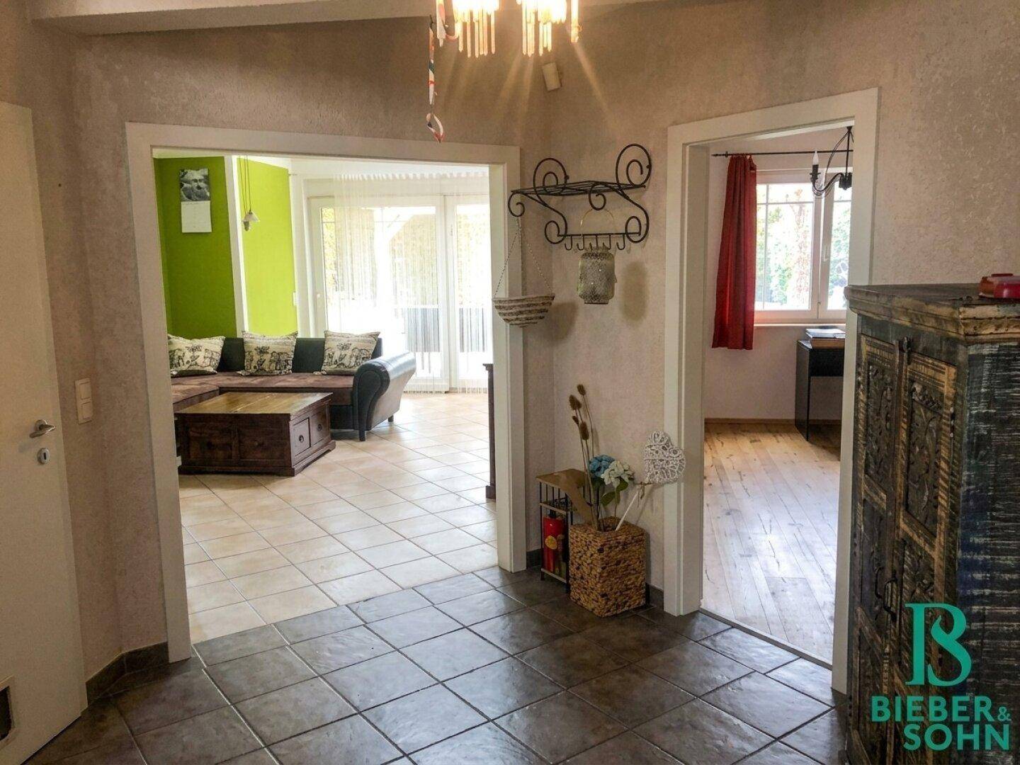 Flur mit Fliesenboden, der zu einem Wohnzimmer und einem weiteren Raum führt.