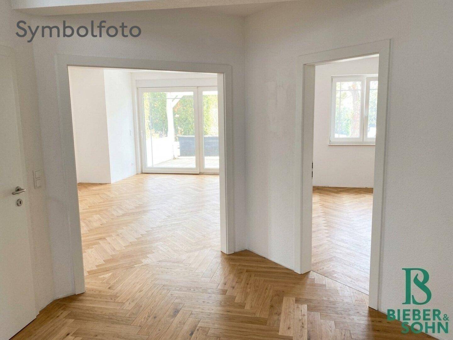 Heller Flur mit Fischgrätparkett und offenen Türen zu angrenzenden Räumen.