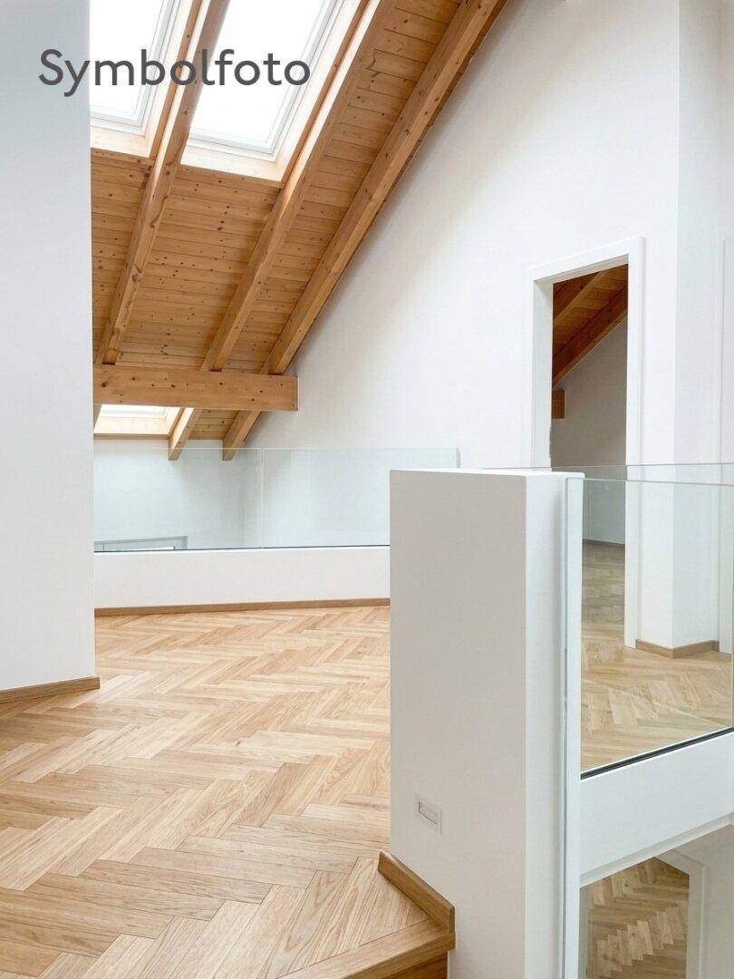 Modernes Dachgeschoss mit Fischgrätparkett, Glasgeländer und sichtbaren Holzbalken unter Dachfenstern.