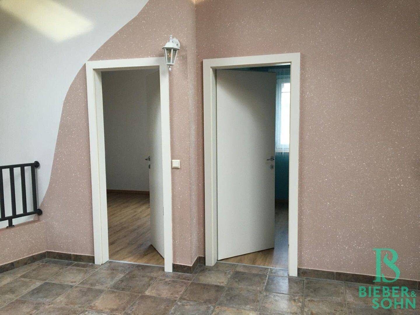 Flur im Dachgeschoss mit Fliesenboden und zwei Türen zu angrenzenden Räumen.