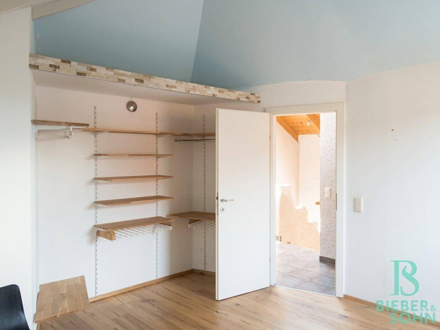 Schlafzimmer im Dachgeschoss mit begehbarem Kleiderschrank und Holzboden.