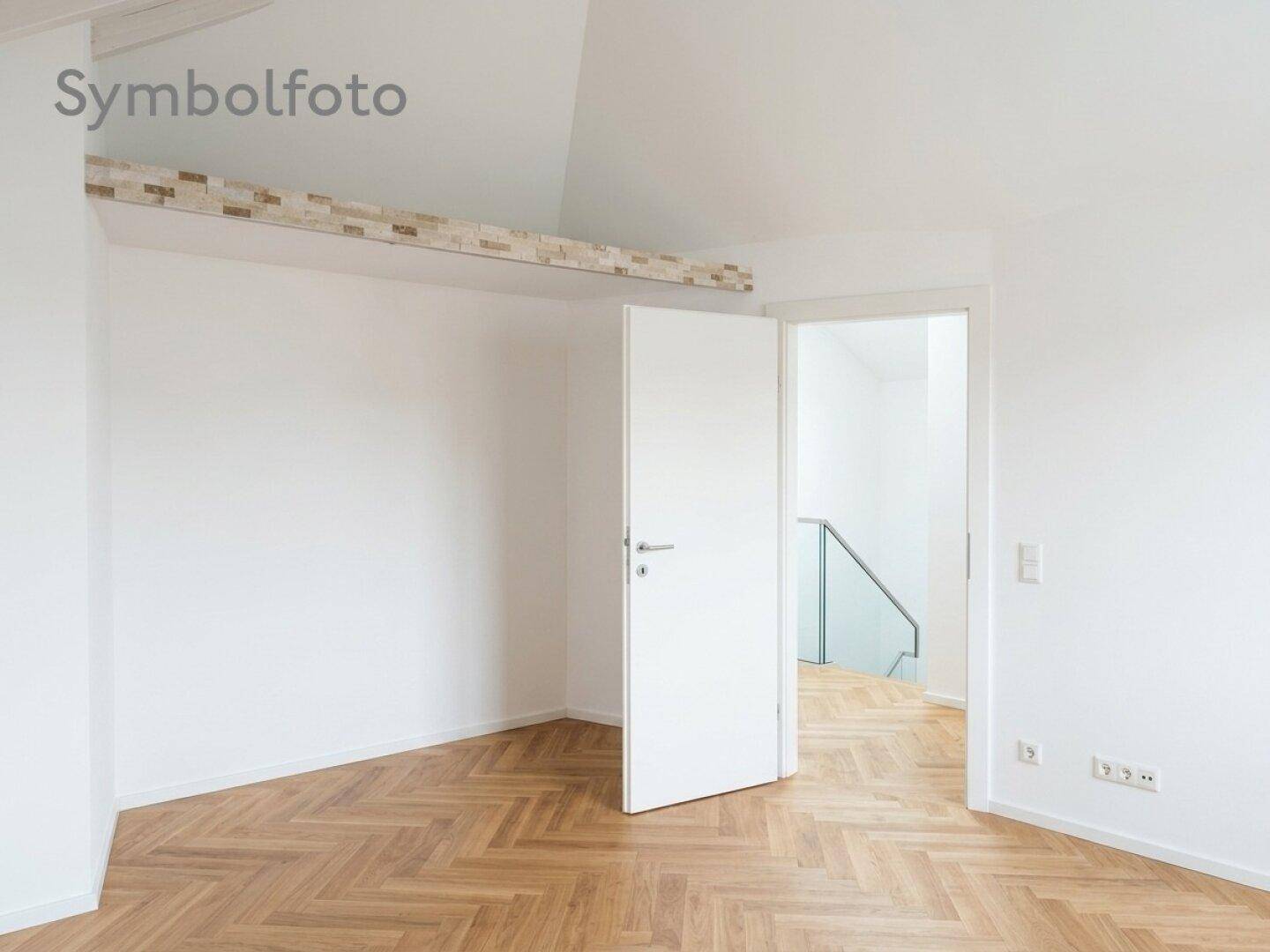 Helles Schlafzimmer im Dachgeschoss mit Fischgrätparkett und offenem Zugang zu einem Ankleidebereich.