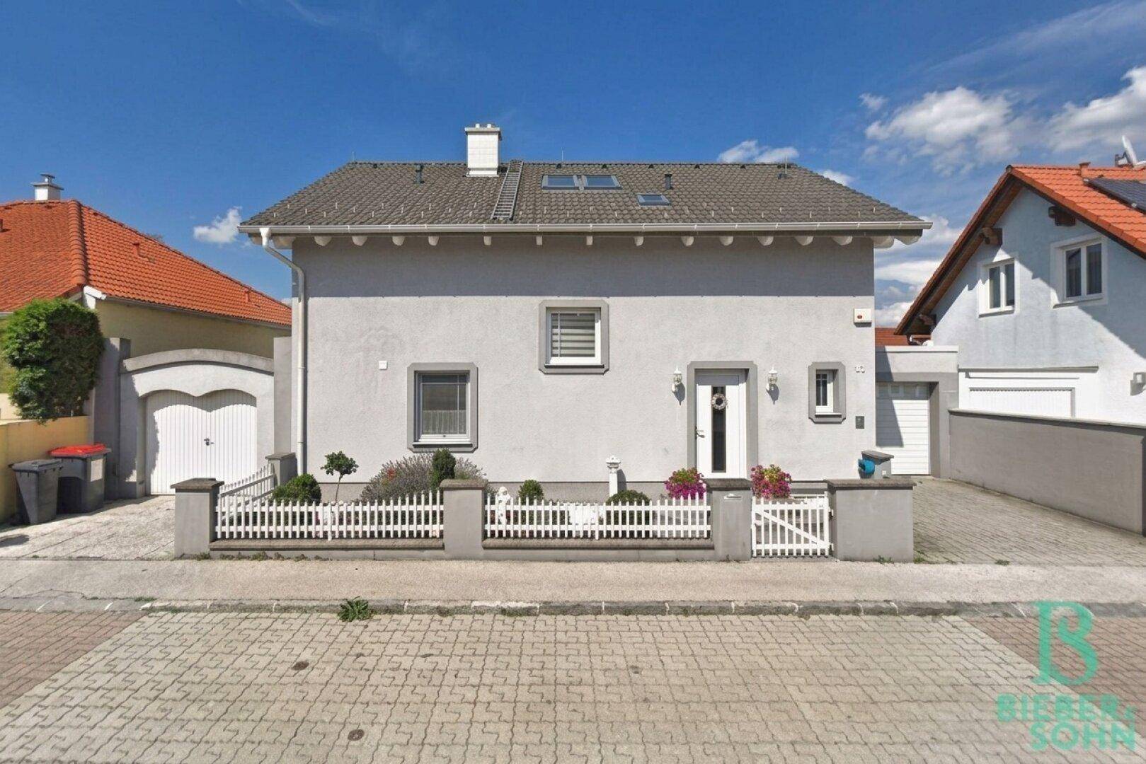 Vorderansicht eines gepflegten Einfamilienhauses mit kleinem Vorgarten und Garage.
