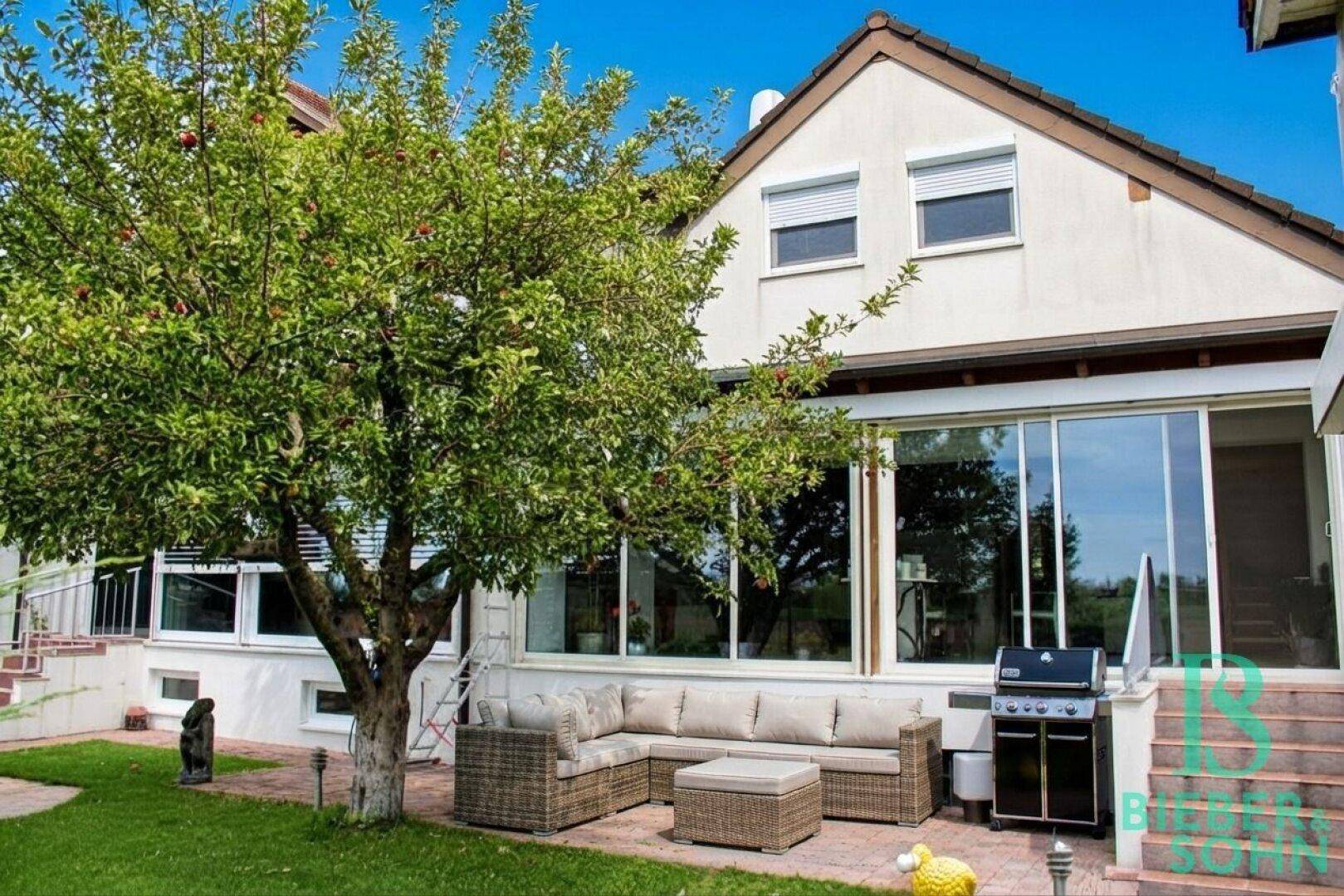 Geräumige Terrasse mit Lounge-Möbeln, Grill und Zugang zum Garten.