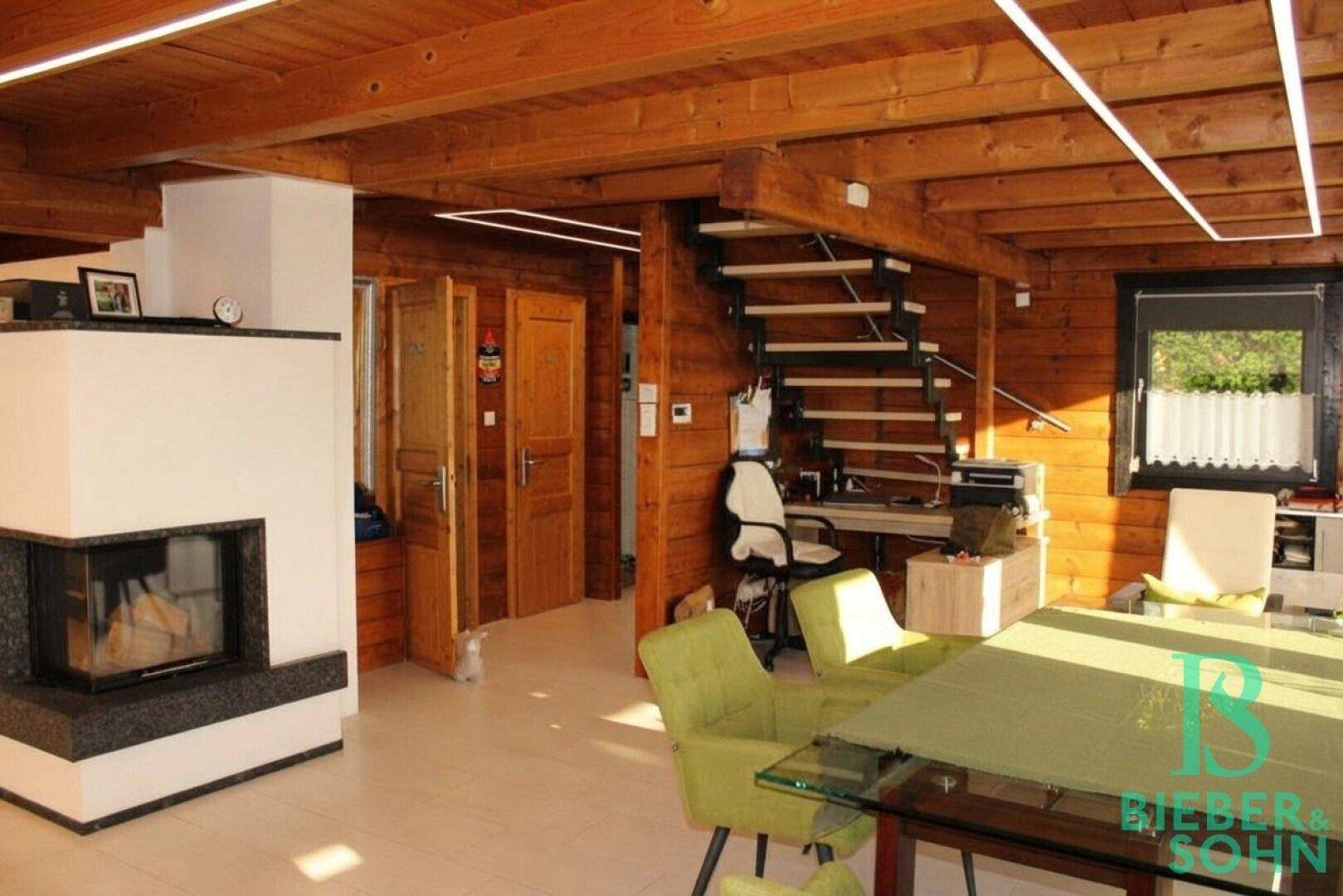 Gemütlicher Wohnbereich mit Holzbalken, Kamin und offener Treppe.