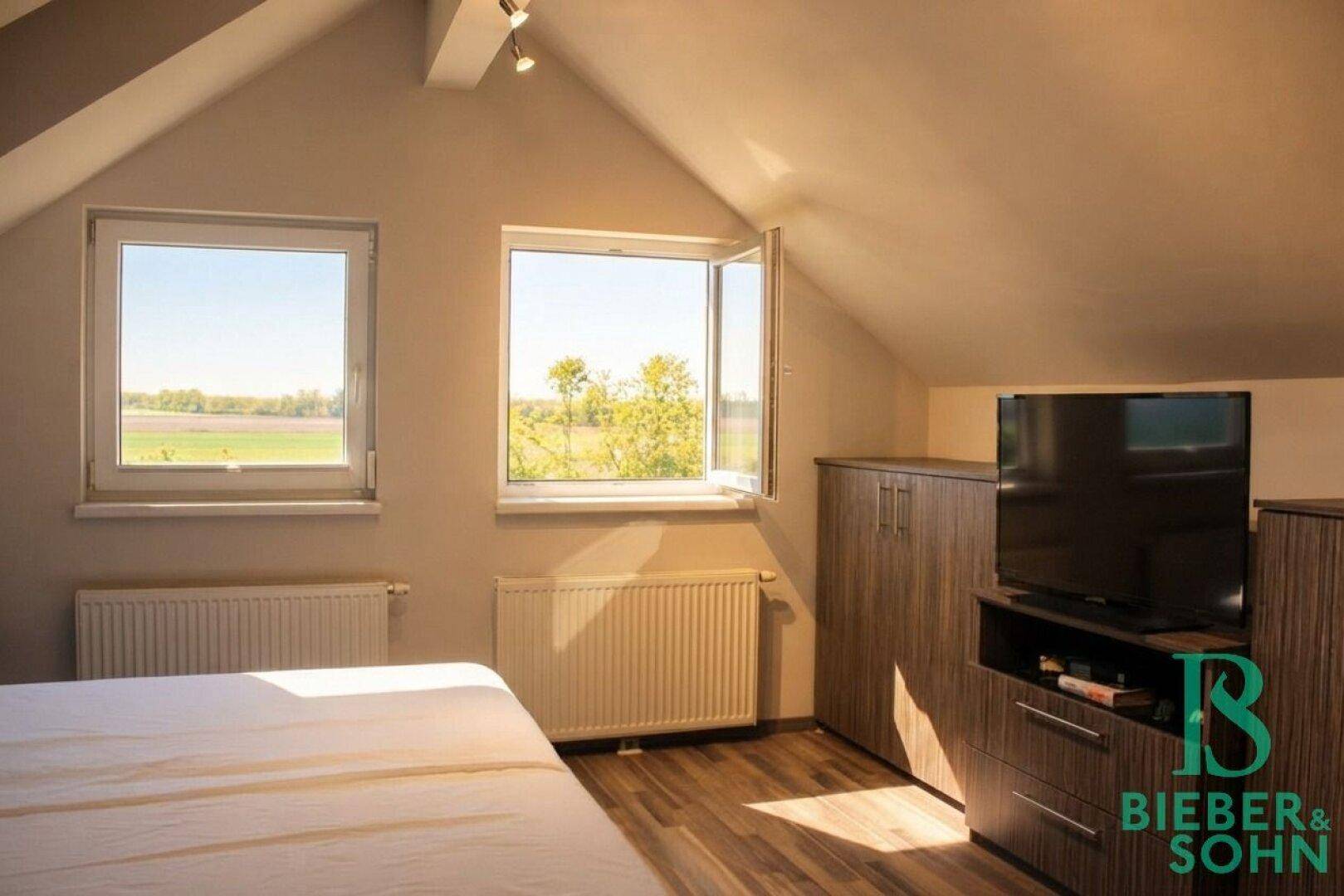 Gemütliches Schlafzimmer mit Holzboden, Dachschrägen und weitem Ausblick.