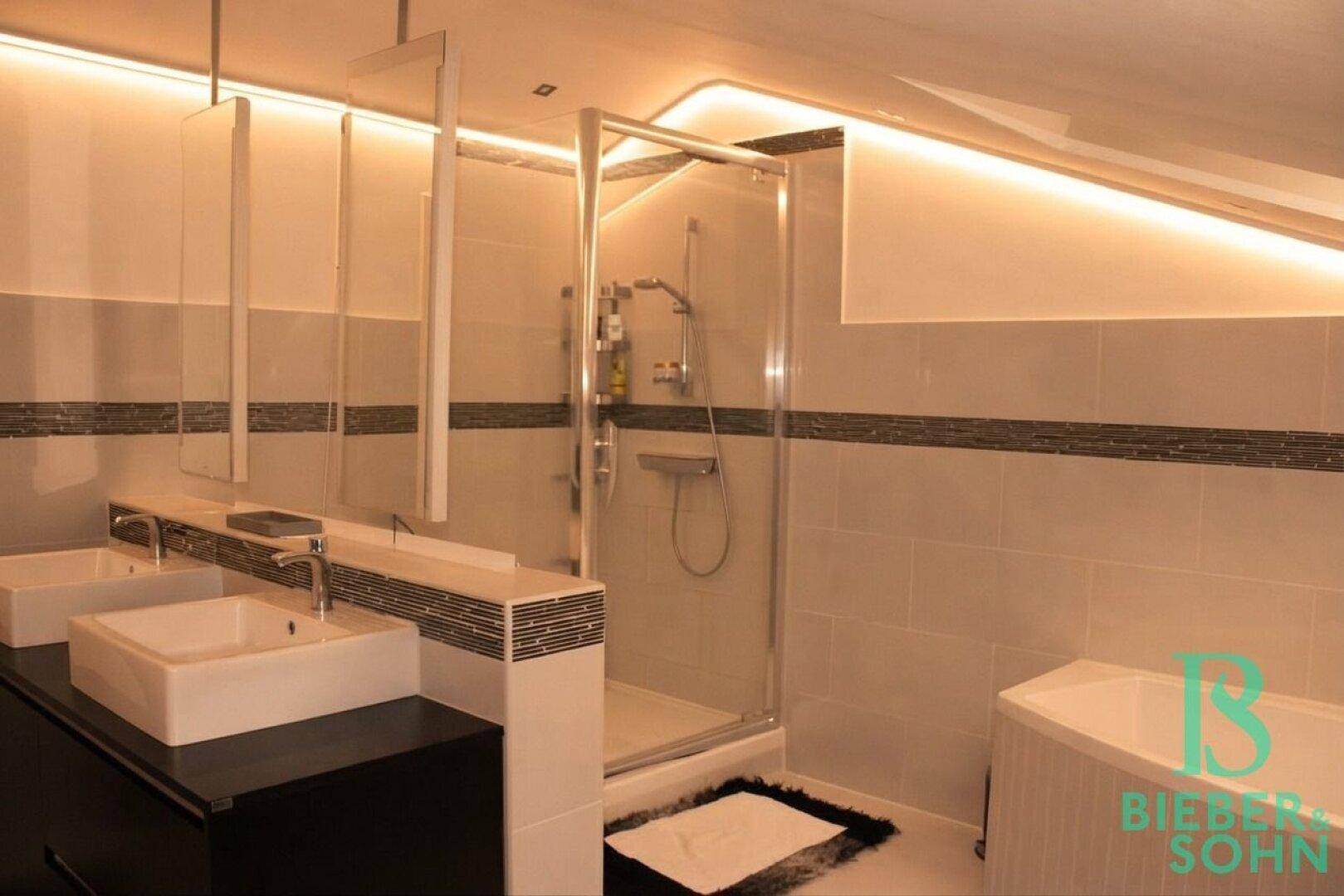 Elegantes Badezimmer mit großer Duschkabine, Doppelwaschbecken und stilvoller indirekter Beleuchtung.
