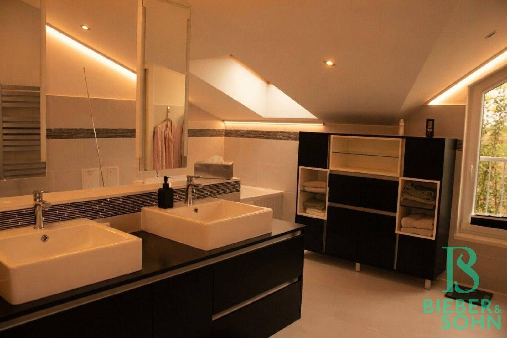 Geräumiges Badezimmer mit zwei Waschbecken, großem Spiegel und praktischem Stauraum.