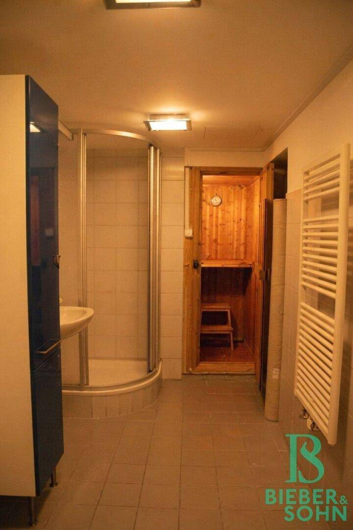 Badezimmer im Untergeschoss mit Dusche, Waschbecken, Handtuchheizkörper und Saunazugang.