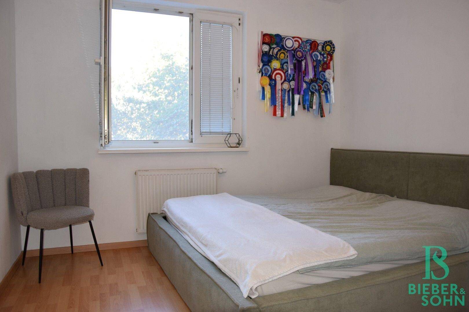 Helles Schlafzimmer mit großem Fenster, bequemen Bett und schlichtem Design.