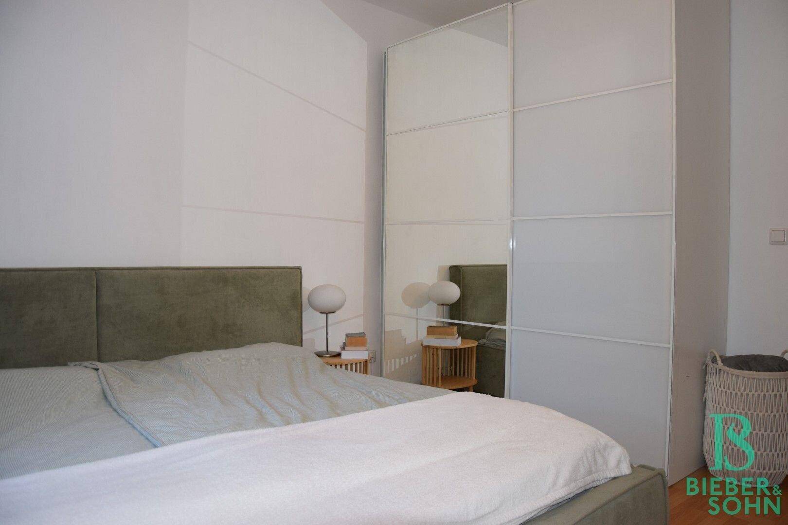 Schlafzimmer mit großem Bett und einem geräumigen Spiegelschrank, der den Raum optisch vergrößert.